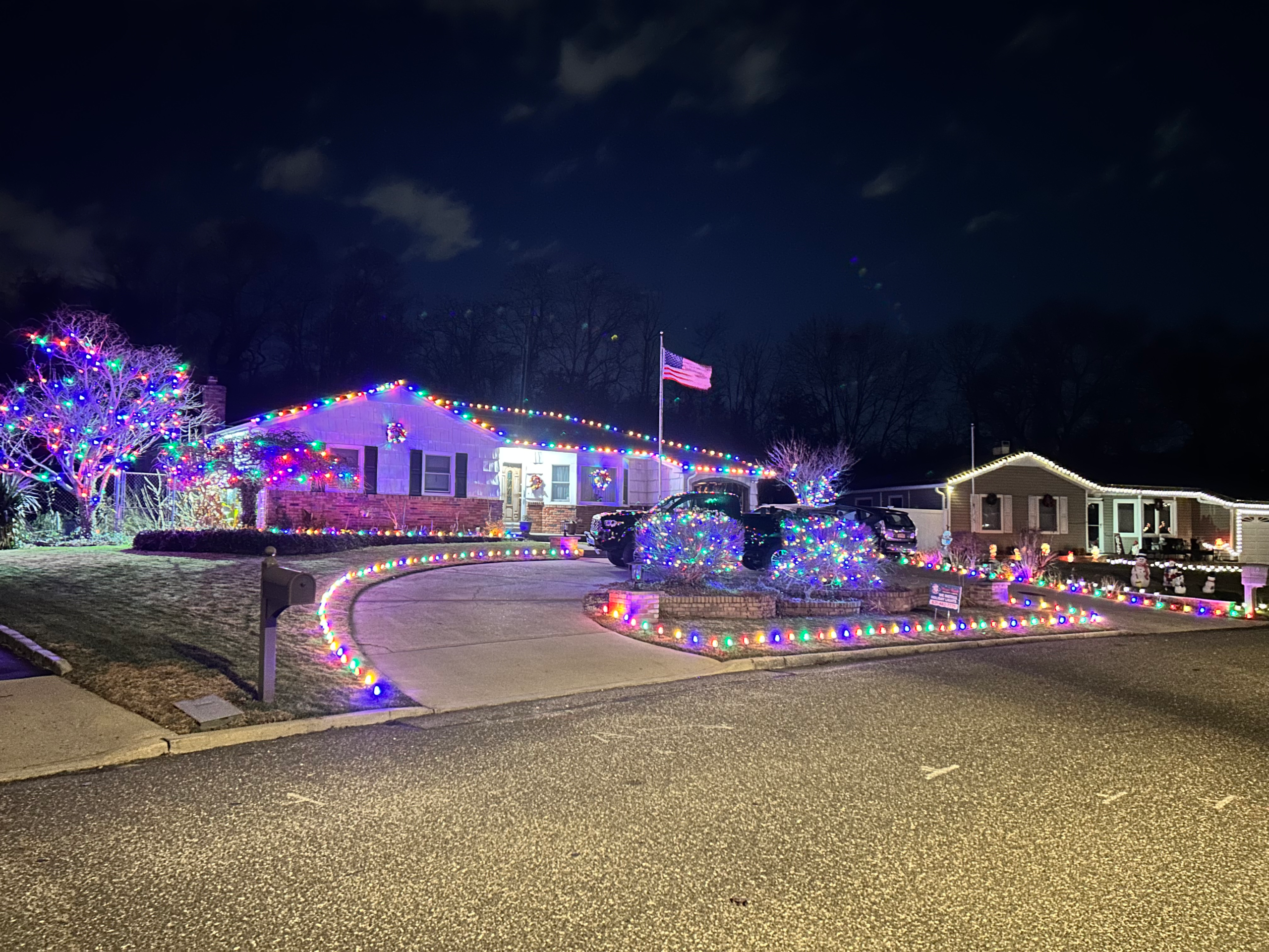 Christmas Light Installation Suffolk County NY on a home with colorful roofline, landscaping, tree, and driveway lights